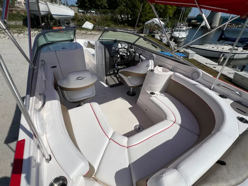 Slide: The Image of 2009 Rinker 246 Captiva Bowrider with spacious seating and sleek design in a marina setting. - 18