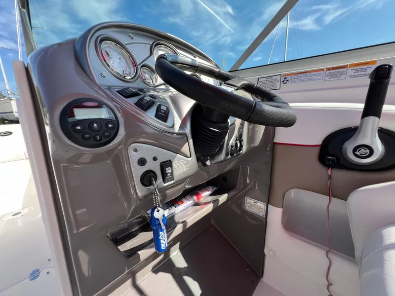 Slide: The Image of 2009 Rinker 246 Captiva Bowrider dashboard with steering wheel and controls under blue sky. - 20
