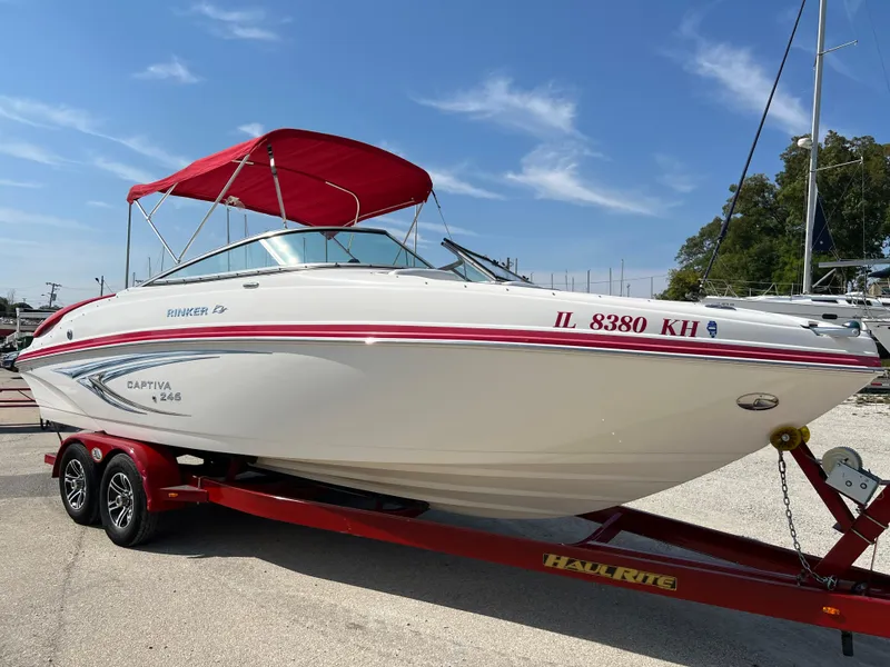 Slide: The Image of 2009 Rinker 246 Captiva Bowrider with red canopy on trailer, parked outdoors. - 7