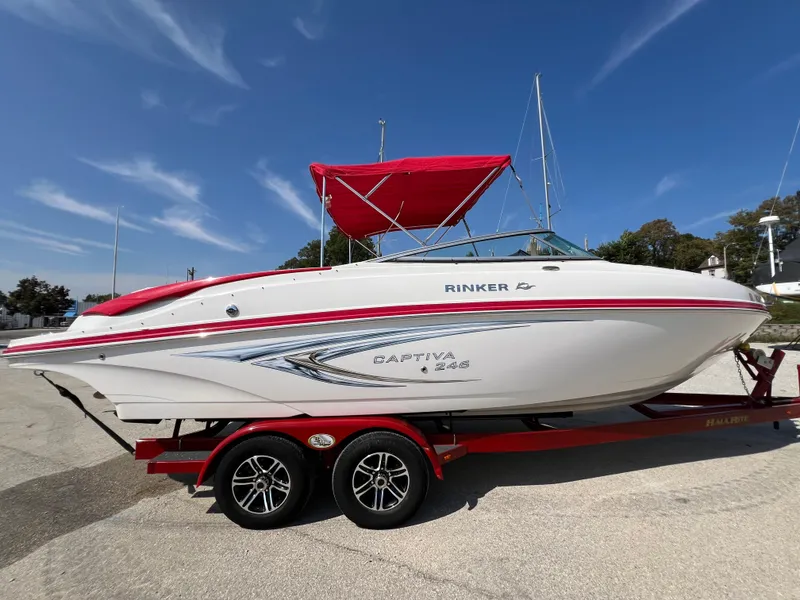 Slide: The Image of 2009 Rinker 246 Captiva Bowrider on red trailer with canopy, parked outdoors. - 8