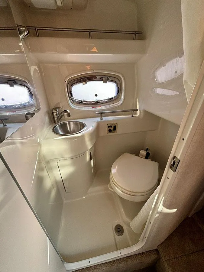 Slide: The Image of 2012 Sea Ray 260 Sundancer bathroom with sink, toilet, and porthole window. - 12