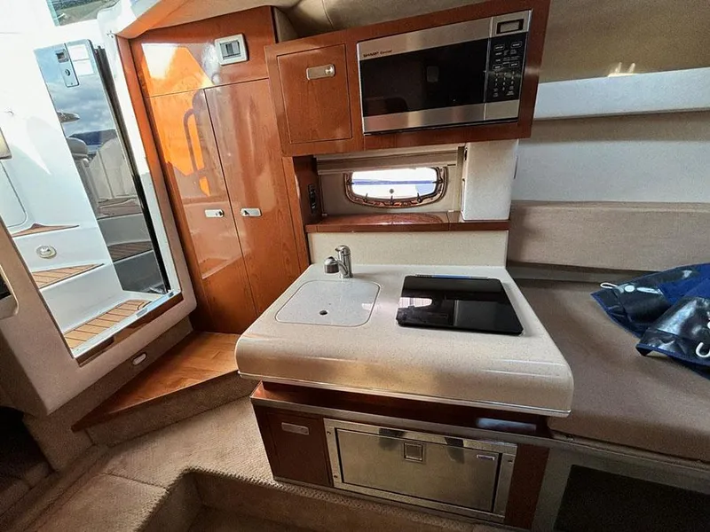 Slide: The Image of Interior of 2012 Sea Ray 260 Sundancer with kitchenette, microwave, and seating area. - 9