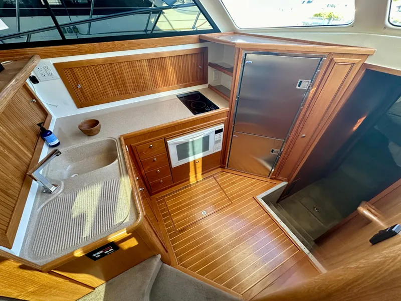 Slide: The Image of 1998 Riviera 43 yacht kitchen with wood cabinetry, sink, stove, and microwave. - 16