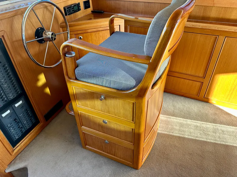 Slide: The Image of Captain's chair in 1998 Riviera 43 yacht cockpit, featuring wooden design and steering wheel. - 23