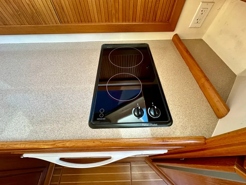 Slide: The Image of Electric stovetop in 1998 Riviera 43 yacht kitchen, featuring two burners and wooden cabinetry. - 24