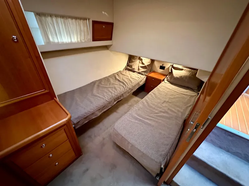 Slide: The Image of 1998 Riviera 43 yacht cabin with twin beds and wooden cabinetry. - 27