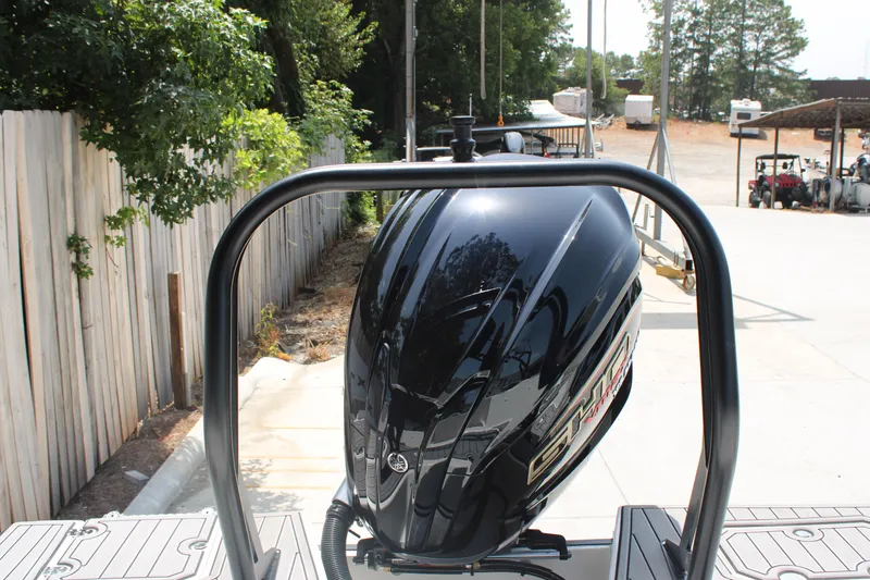 Slide: The Image of 2025 Starcraft 230 boat engine, black, parked outdoors near wooden fence and trees. - 20