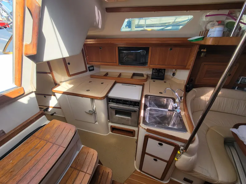 Slide: The Image of Interior of 2003 Catalina 42 Mk2 sailboat, featuring a compact kitchen with wood accents. - 3