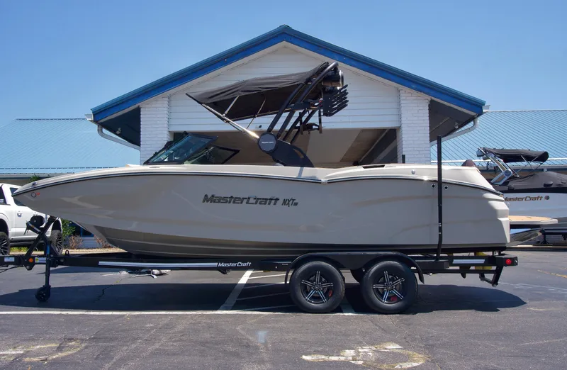 The Image of 2025 MasterCraft NXT22 boat on trailer, parked in front of a building. - 1