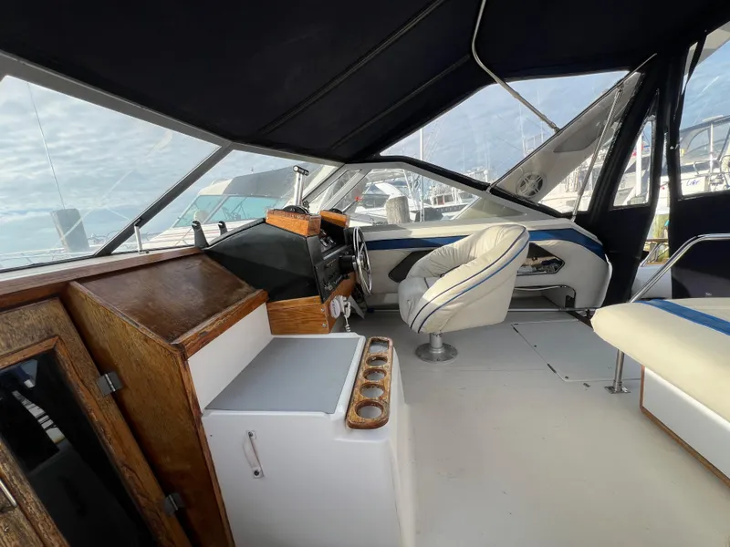 Slide: The Image of Interior of 1985 Bayliner 3250 Conquest boat with helm and seating area. - 2