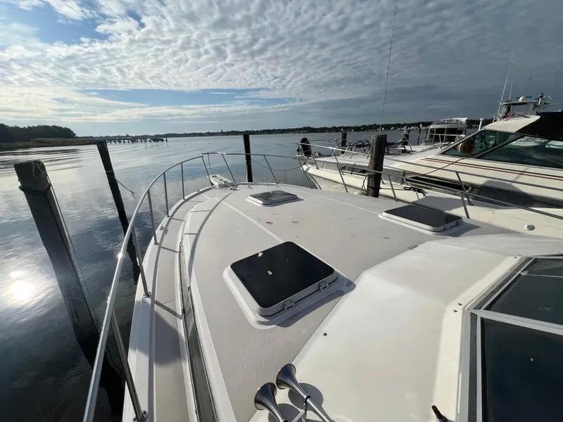Slide: The Image of 1985 Bayliner 3250 Conquest boat docked on a calm, scenic waterfront. - 29