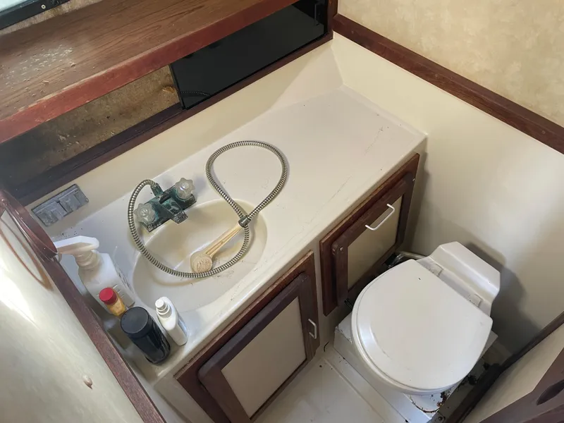 Slide: The Image of 1983 Luhrs 340 boat bathroom with sink, toilet, and storage cabinets. - 16