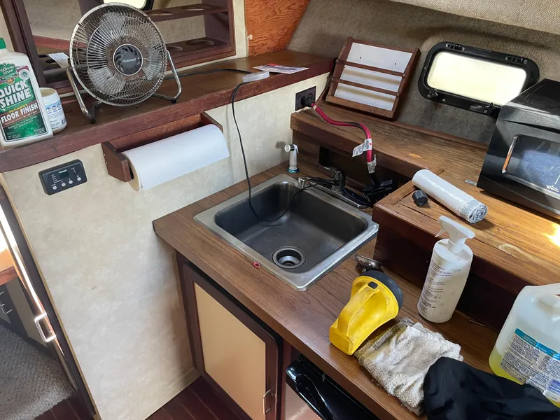 Slide: The Image of 1983 Luhrs 340 boat kitchen with sink, fan, and cleaning supplies. - 18