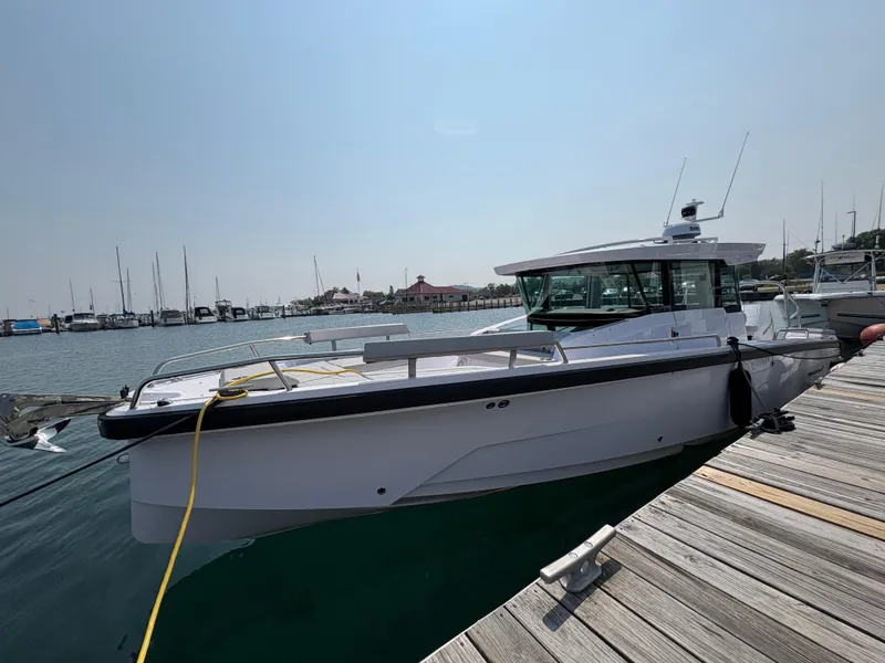 Slide: The Image of 2025 Axopar 29 XC Cross Cabin docked at a marina, clear sky, calm water. - 1