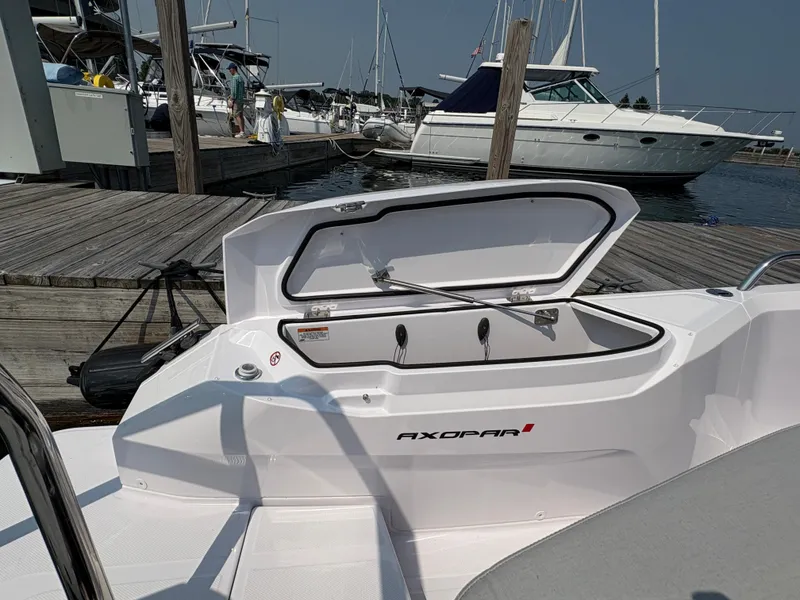 Slide: The Image of 2025 Axopar 29 XC Cross Cabin boat with open storage compartment at marina. - 16