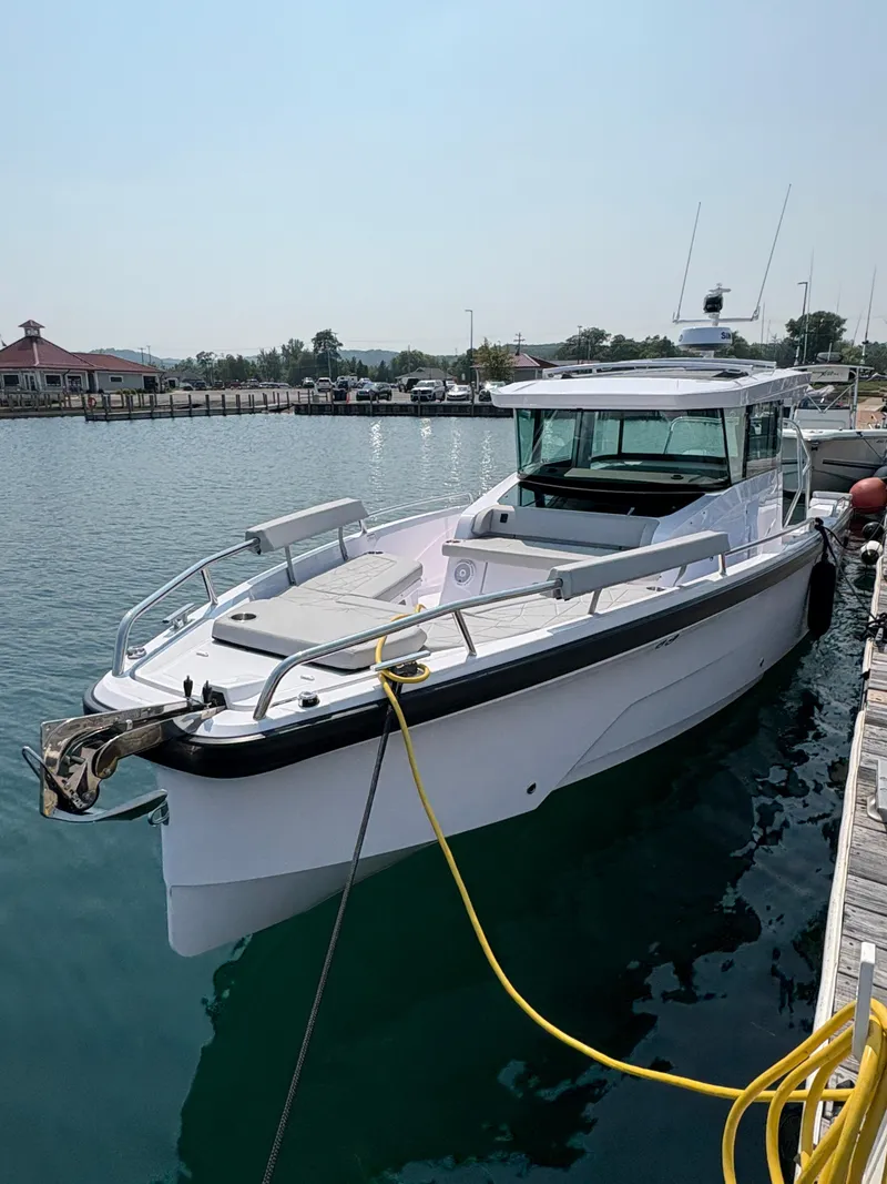 Slide: The Image of 2025 Axopar 29 XC Cross Cabin boat docked at marina, sunny day. - 2