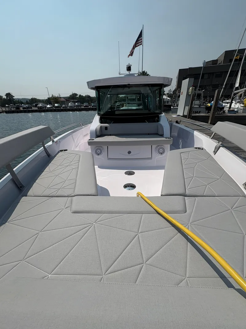 Slide: The Image of 2025 Axopar 29 XC Cross Cabin boat with spacious seating and modern design at a marina. - 26