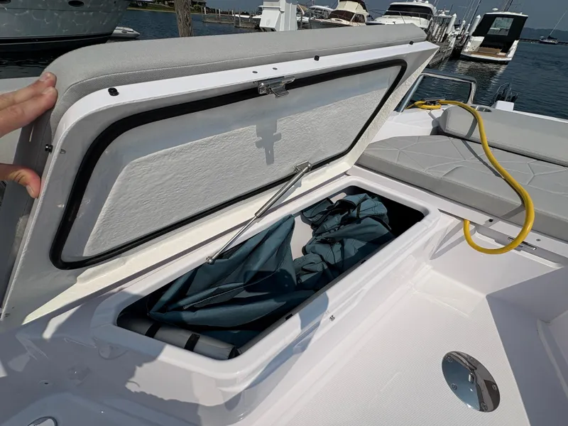Slide: The Image of Storage compartment on 2025 Axopar 29 XC Cross Cabin boat, open with items inside. - 27