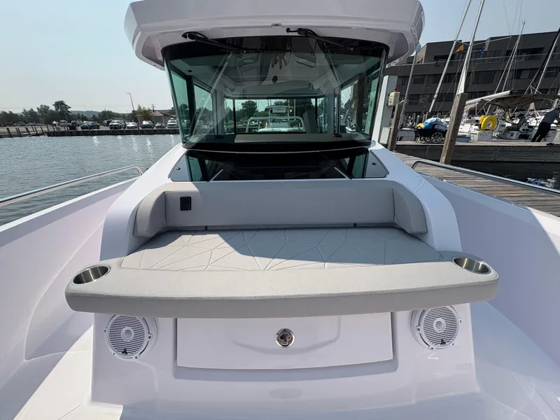 Slide: The Image of 2025 Axopar 29 XC Cross Cabin boat with cushioned seating and cup holders at a marina. - 29