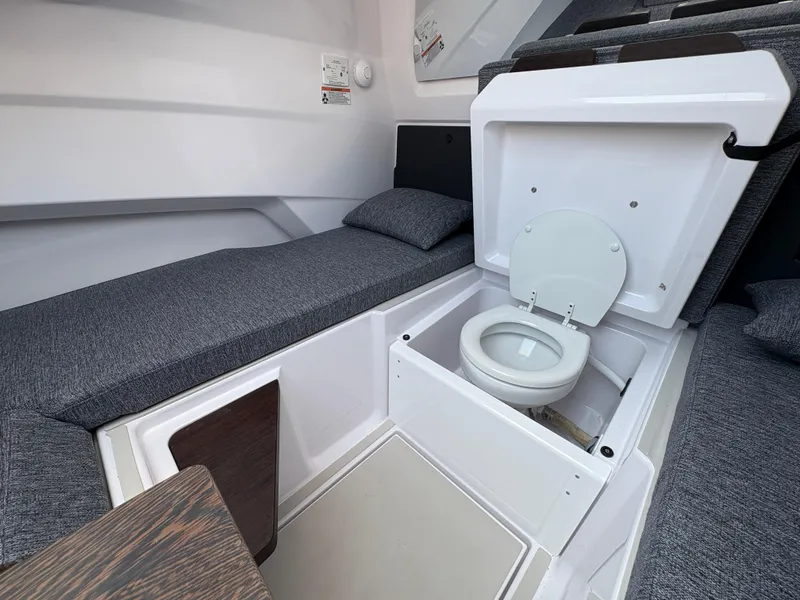 Slide: The Image of 2025 Axopar 29 XC Cross Cabin interior with compact toilet and seating area. - 36