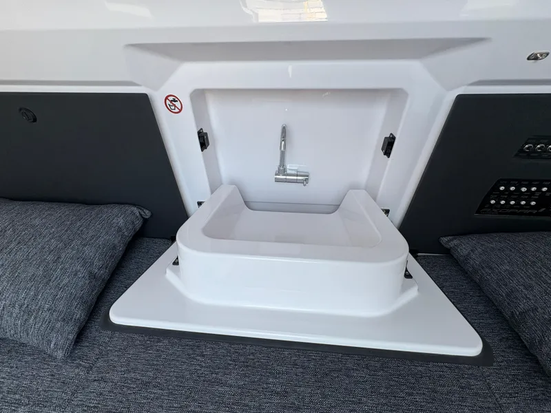 Slide: The Image of 2025 Axopar 29 XC Cross Cabin interior sink with modern design and gray cushions. - 38
