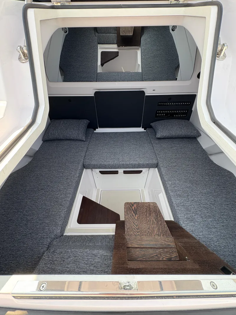 Slide: The Image of 2025 Axopar 29 XC Cross Cabin interior with gray seating and wooden accents. - 40