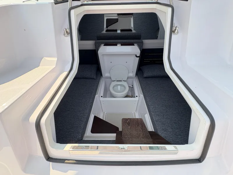 Slide: The Image of 2025 Axopar 29 XC Cross Cabin interior with compact toilet and seating area. - 42