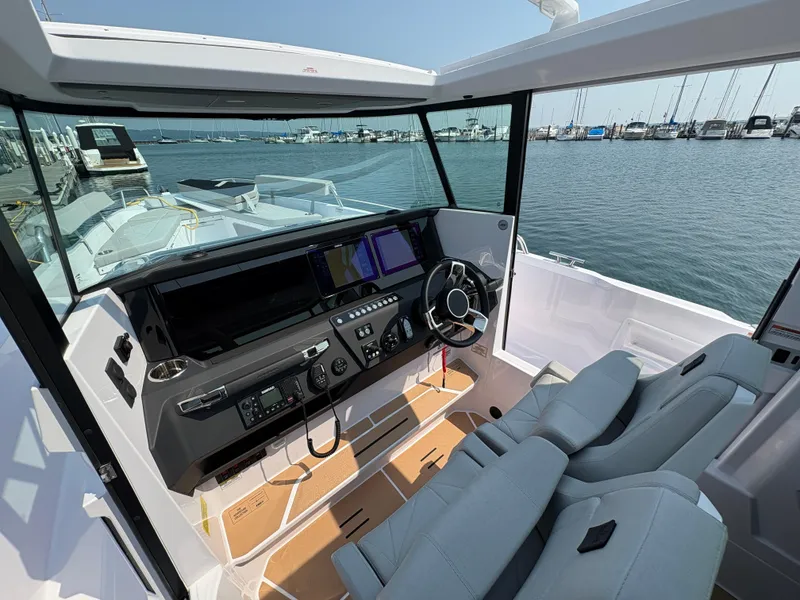 Slide: The Image of 2025 Axopar 29 XC Cross Cabin interior with modern dashboard and waterfront view. - 48