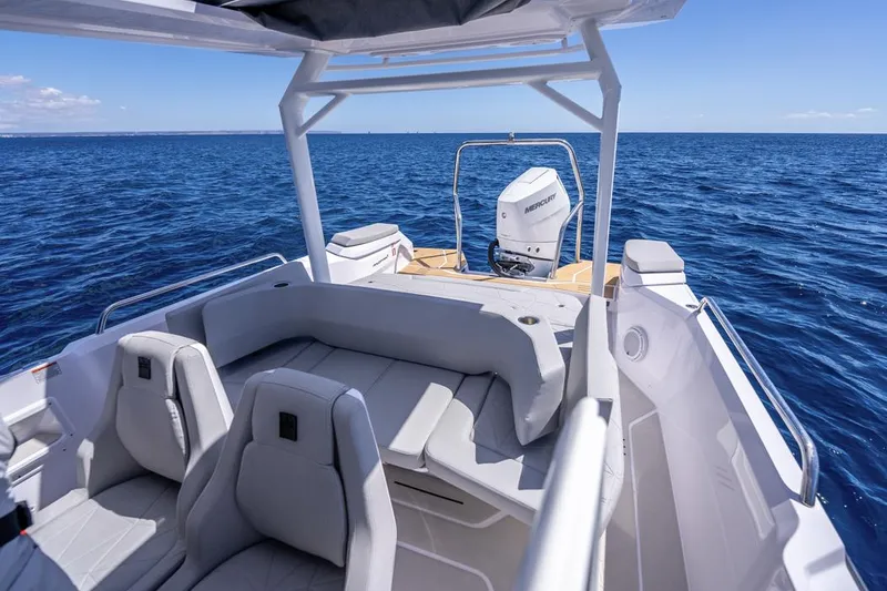 Slide: The Image of 2025 Axopar 29 Sun Top boat interior with ocean view, featuring modern seating and outboard motor. - 21