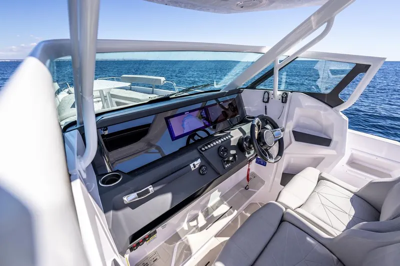Slide: The Image of 2025 Axopar 29 Sun Top boat interior with modern dashboard and steering, ocean view. - 6
