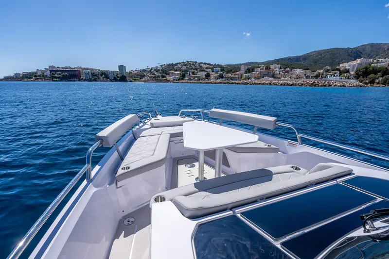 Slide: The Image of 2025 Axopar 29 Sun Top boat with spacious deck, cruising on clear blue waters. - 9