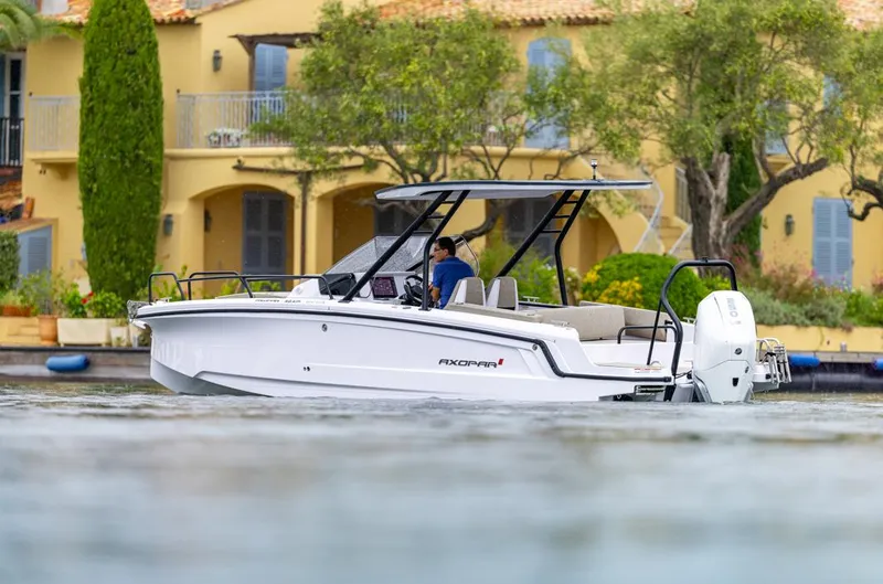 Slide: The Image of 2025 Axopar 25 Cross Top boat with Mercury engine, showcased at an indoor event. - 2