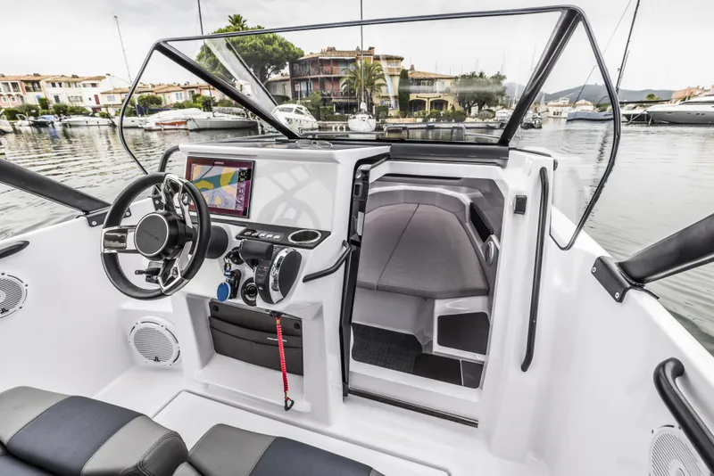 Slide: The Image of 2025 Axopar 25 Cross Top boat showcased at an indoor exhibition with other vessels. - 9