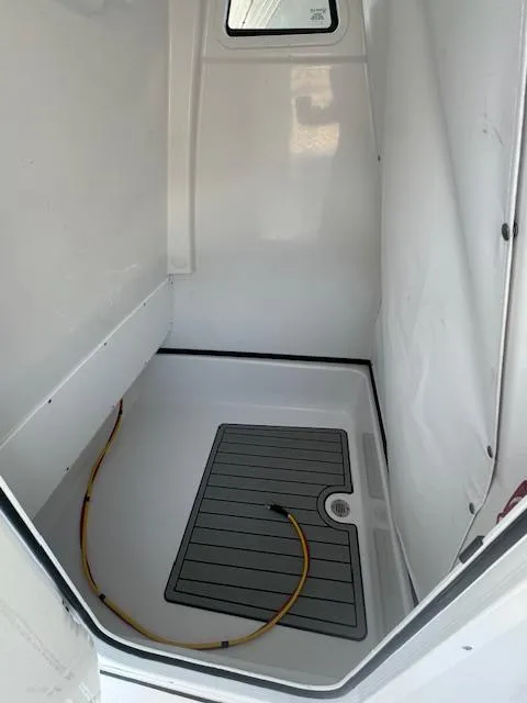 Slide: The Image of 2025 Sportsman Masters 247 Bay Boat interior compartment with hose and non-slip flooring. - 10