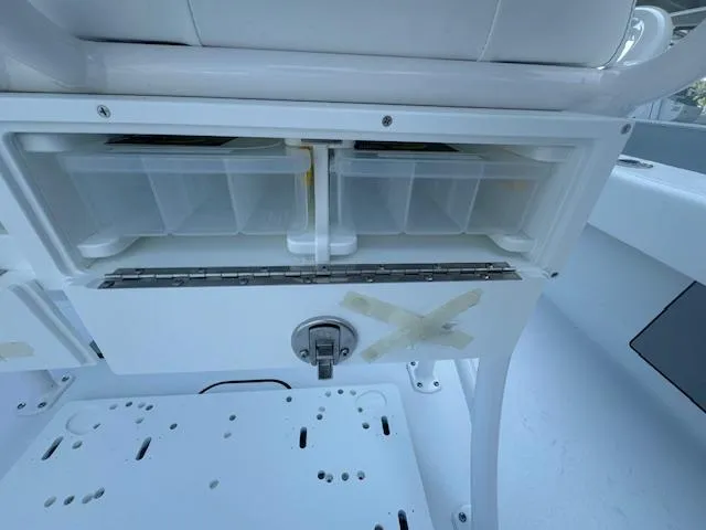 Slide: The Image of 2025 Sportsman Masters 247 Bay Boat storage compartment with tackle boxes and secure latch. - 22