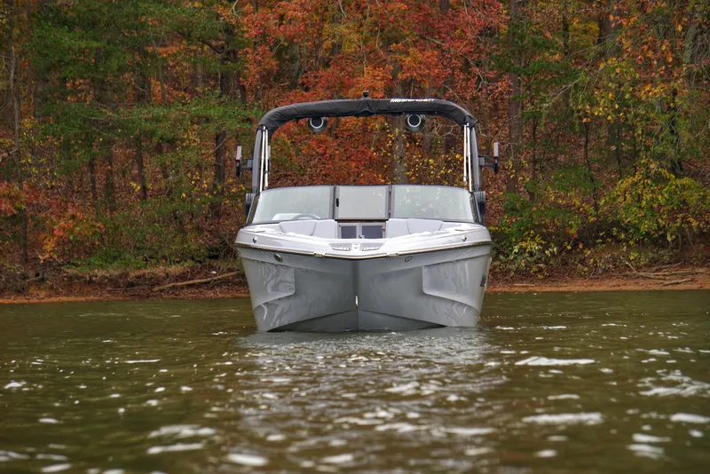 Slide: The Image of 2025 MasterCraft XT23 boat on a lake with autumn foliage background. - 2