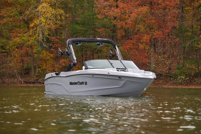 Slide: The Image of 2025 MasterCraft XT23 boat on a lake with autumn foliage background. - 3