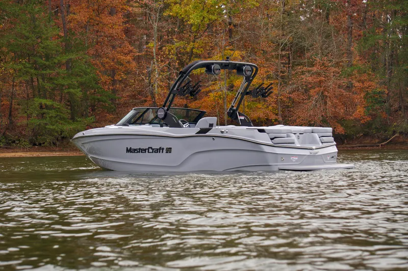 Slide: The Image of 2025 MasterCraft XT23 boat on a lake with autumn foliage background. - 7