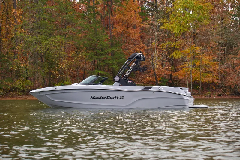 Slide: The Image of 2025 MasterCraft XT23 boat on a lake with autumn trees in the background. - 8