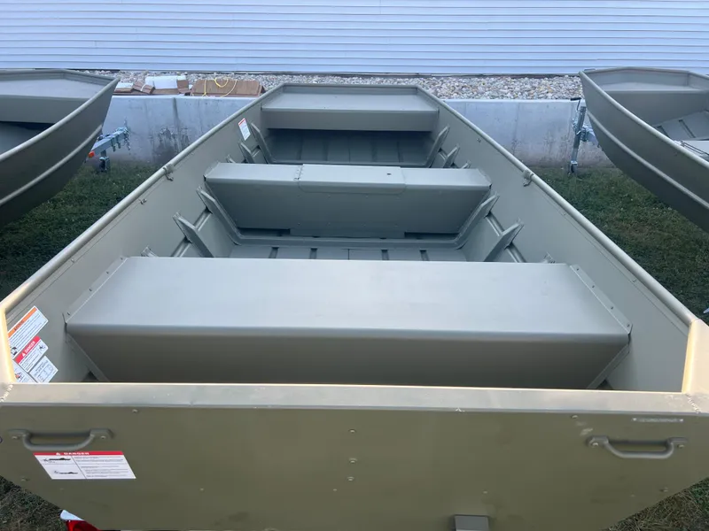 Slide: The Image of 2025 Lund 1448 boat, olive green, aluminum construction, parked outdoors. - 3