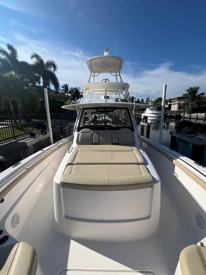 Slide: The Image of 2020 Pursuit S408 boat docked, featuring spacious deck and seating under clear blue sky. - 10