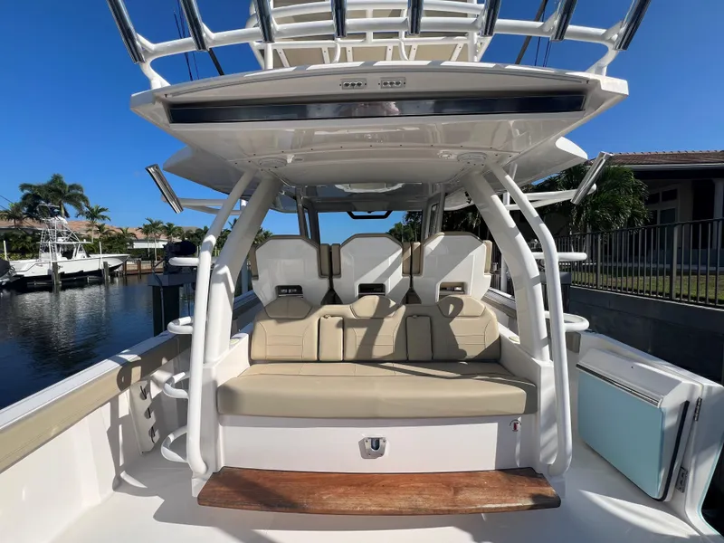 Slide: The Image of 2020 Pursuit S408 boat interior with seating and helm, docked by a waterfront. - 15