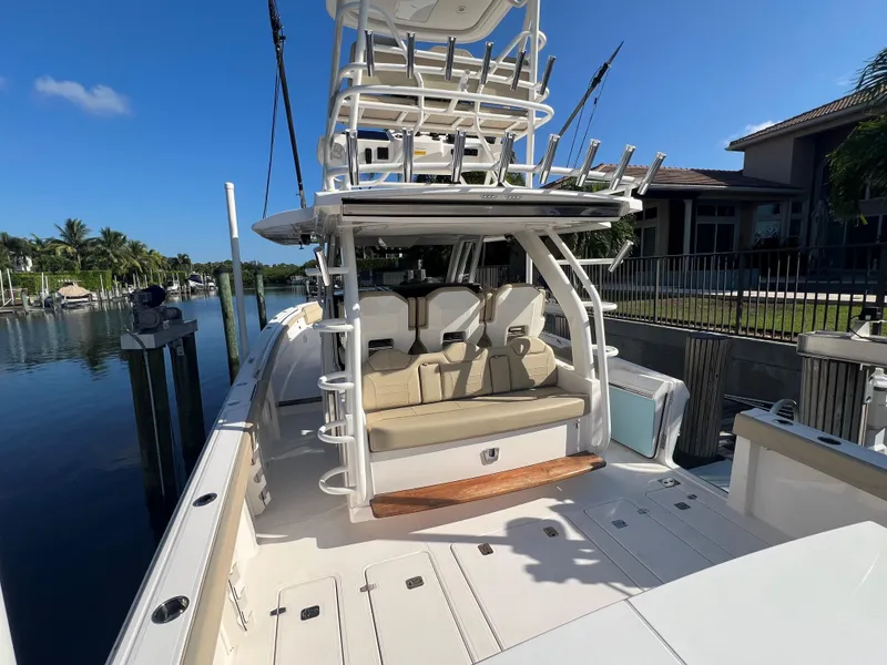 Slide: The Image of 2020 Pursuit S408 boat docked, featuring spacious deck and seating area under clear blue sky. - 16