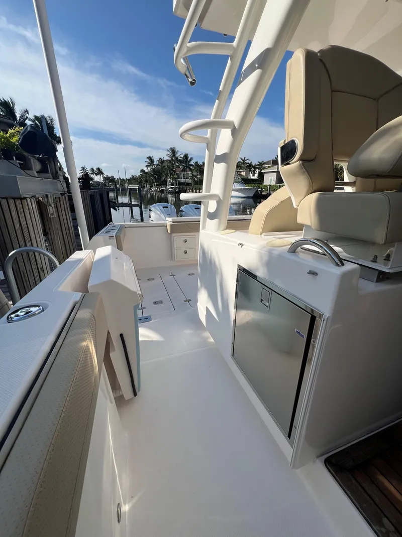 Slide: The Image of 2020 Pursuit S408 boat interior with seating and storage, docked near palm trees. - 17