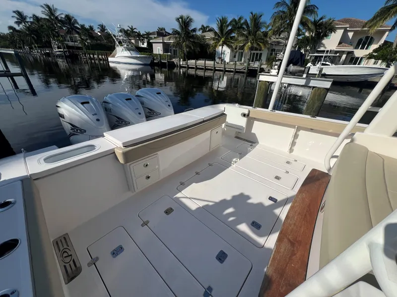 Slide: The Image of 2020 Pursuit S408 boat deck with triple outboard engines, docked by waterfront homes. - 19