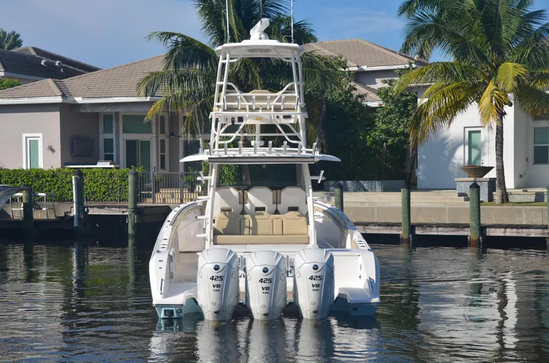 Slide: The Image of 2020 Pursuit S408 boat docked by waterfront homes with palm trees. - 2