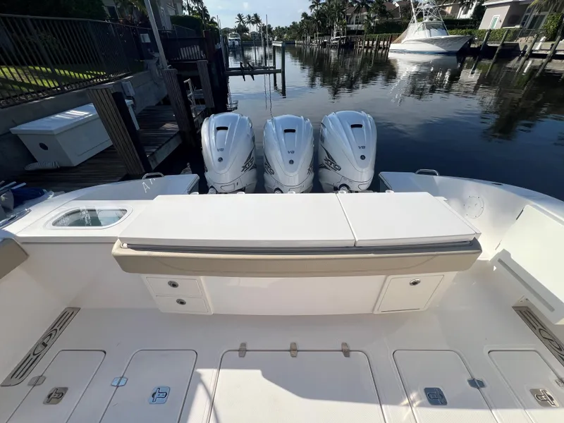 Slide: The Image of 2020 Pursuit S408 boat with triple outboard engines docked by a serene waterfront. - 21