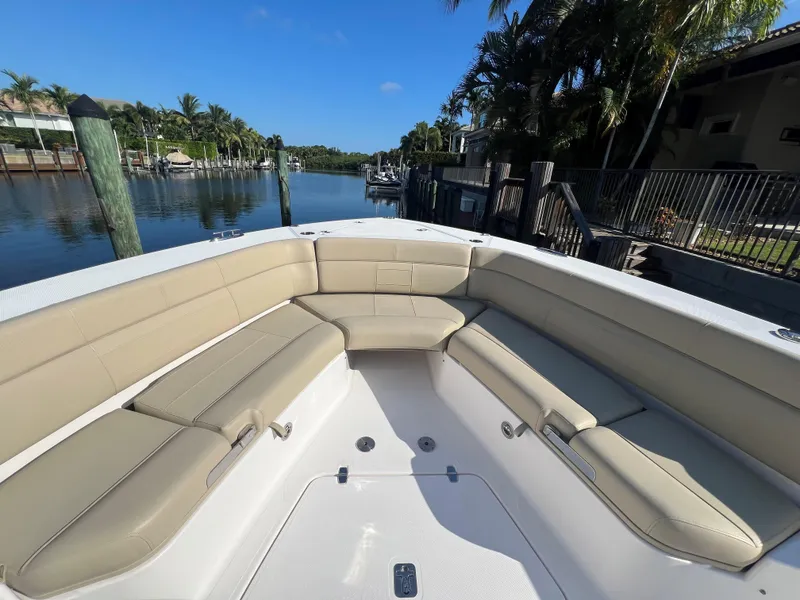 Slide: The Image of 2020 Pursuit S408 boat with beige seating, docked by a scenic waterfront. - 7