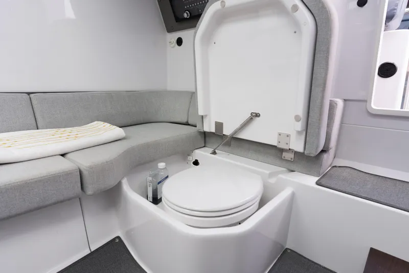 Slide: The Image of 2023 Axopar 37XC CROSS CABIN interior with compact marine toilet and seating area. - 12