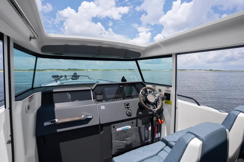 Slide: The Image of Interior view of 2023 Axopar 37XC CROSS CABIN, showcasing helm and seating with ocean backdrop. - 4
